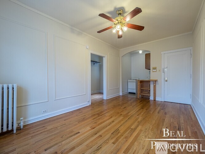 A room with a ceiling fan and wooden floors.