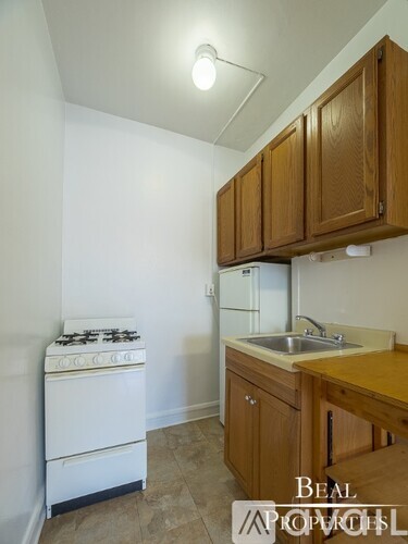 A kitchen with a stove, sink and cabinets.