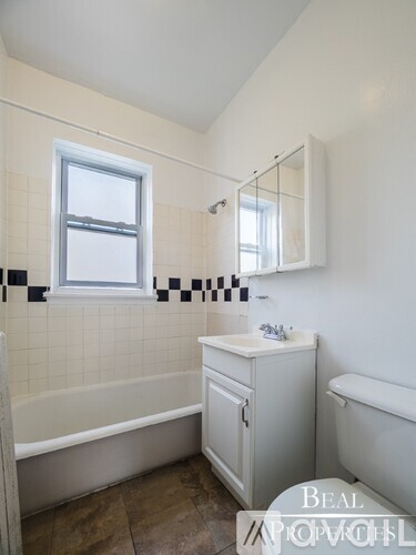 A white bathroom with a tub, sink, and mirror.