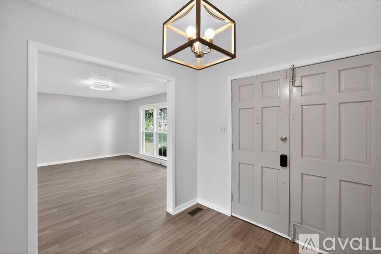 A room with a wooden floor, a white door, and a light fixture on the ceiling.