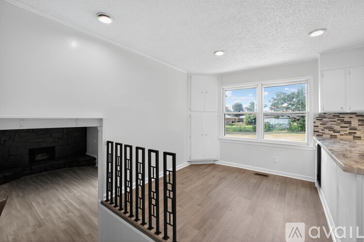A spacious living room with a fireplace and a view of the outdoors through the window.