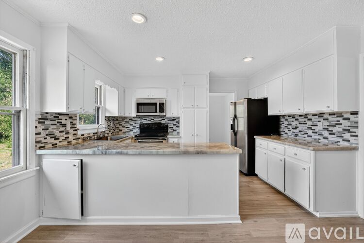 A kitchen with white cabinets and a black refrigerator.