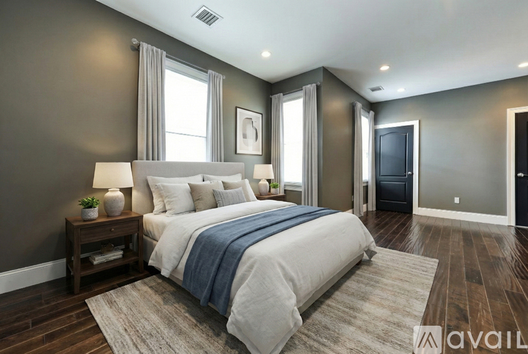 A bedroom with a large bed and a wooden floor.