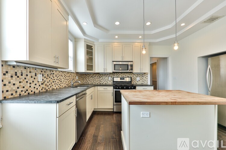 A kitchen with white cabinets and a black and white tiled backsplash.