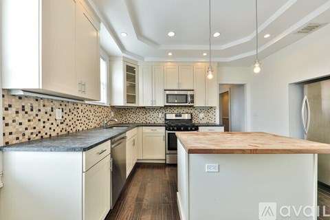 A kitchen with white cabinets and a black and white tiled backsplash.