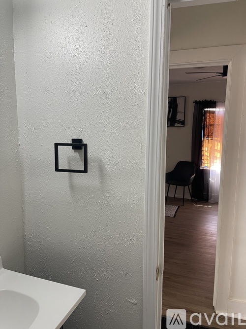 A bathroom with a toilet and a doorway leading to a living room.