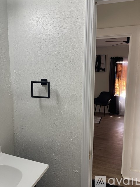 A bathroom with a toilet and a doorway leading to a living room.