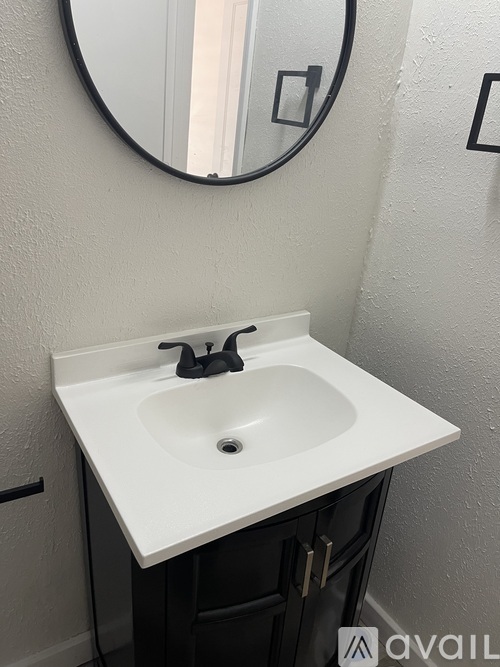 A bathroom sink with a round mirror above it.