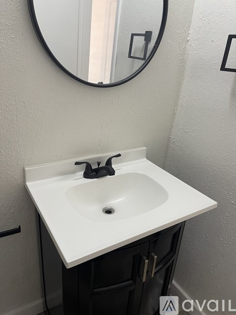 A bathroom sink with a round mirror above it.