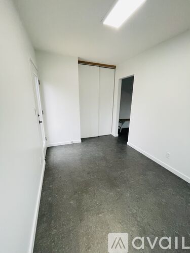 A room with a grey floor and white walls with a door in the middle.