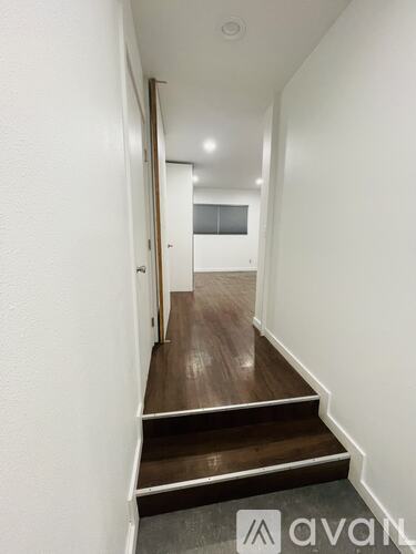 A hallway with a wooden floor and white walls.