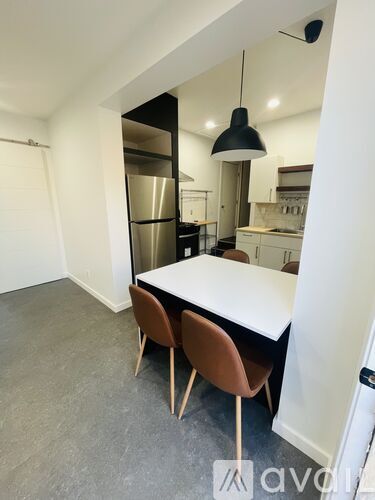 A kitchen with a table and chairs in the foreground and a refrigerator in the background.