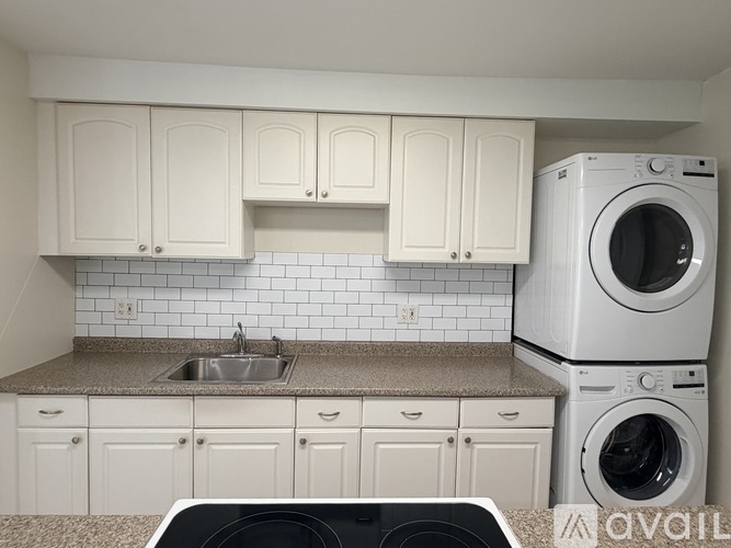 A white kitchen with a washer and dryer stacked on top of each other.