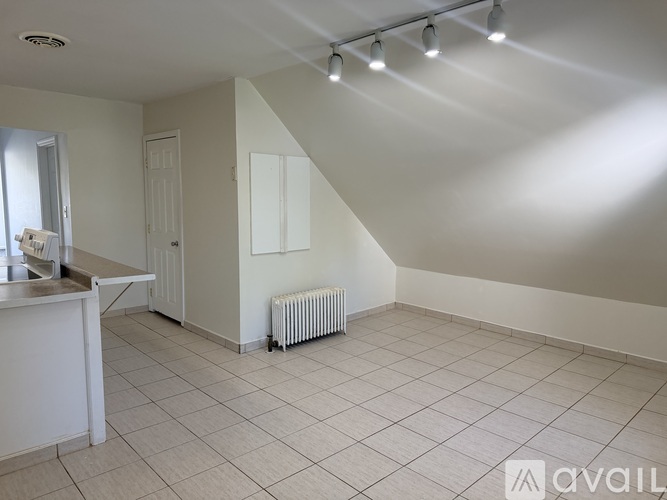 A spacious room with a kitchen area and a radiator.