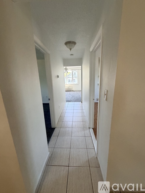 A long hallway with tiled floors and white walls.