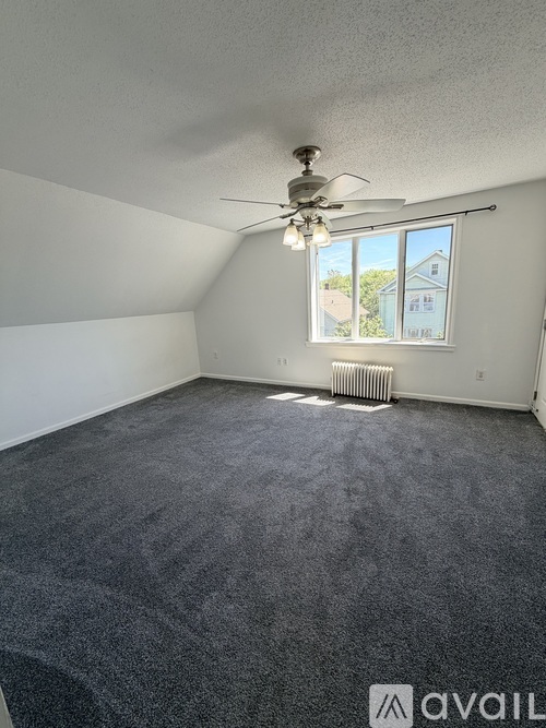 A room with a ceiling fan and a window with a view of a house outside.