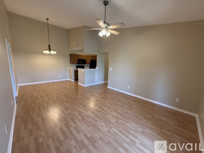 A spacious room with wooden flooring and a ceiling fan.