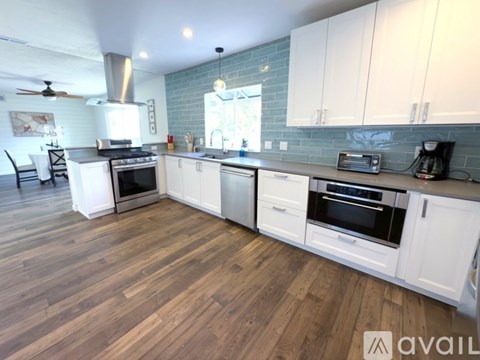 A kitchen with white cabinets and a wooden floor.