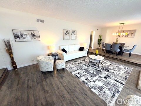 A living room with a white couch, a coffee table, and a rug with a black and white pattern.