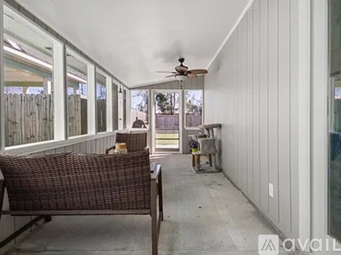 A patio with a brown wicker chair and a ceiling fan.