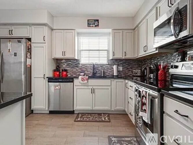 A kitchen with white cabinets and a black countertop.