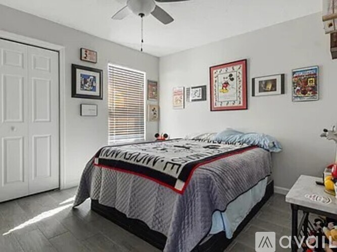 A bedroom with a bed, a ceiling fan, and pictures on the wall.