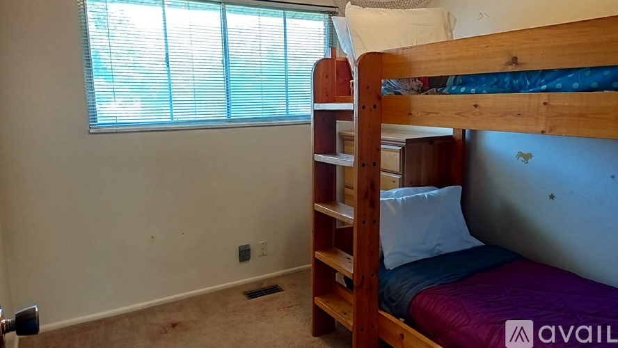 A bedroom with a bunk bed and a window with blinds.