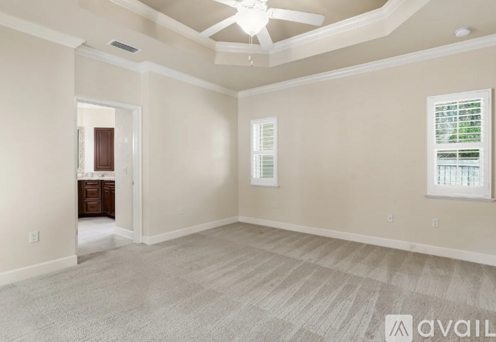 A spacious room with a carpeted floor and a ceiling fan.