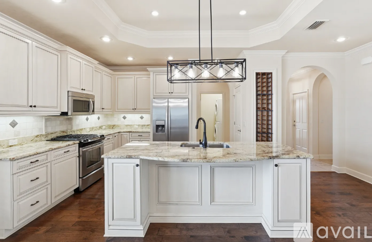 A kitchen with white cabinets and a marble countertop.