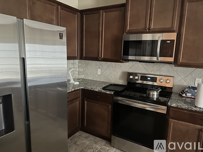 A kitchen with brown cabinets and a stainless steel refrigerator.