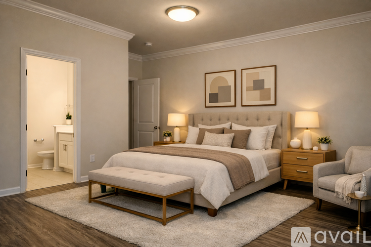 A well-lit bedroom with a large bed, a chair, and a nightstand with lamps.