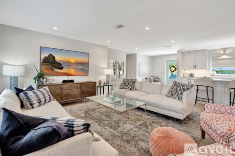 A living room with a large painting of a beach scene on the wall.