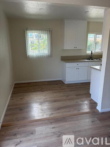 A kitchen with white cabinets and a window with a view of trees.