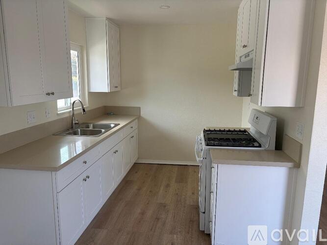 A kitchen with white cabinets and a white fridge.