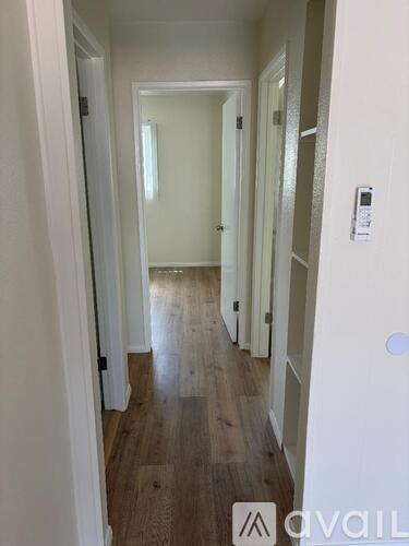 A hallway with wooden floors and white walls.