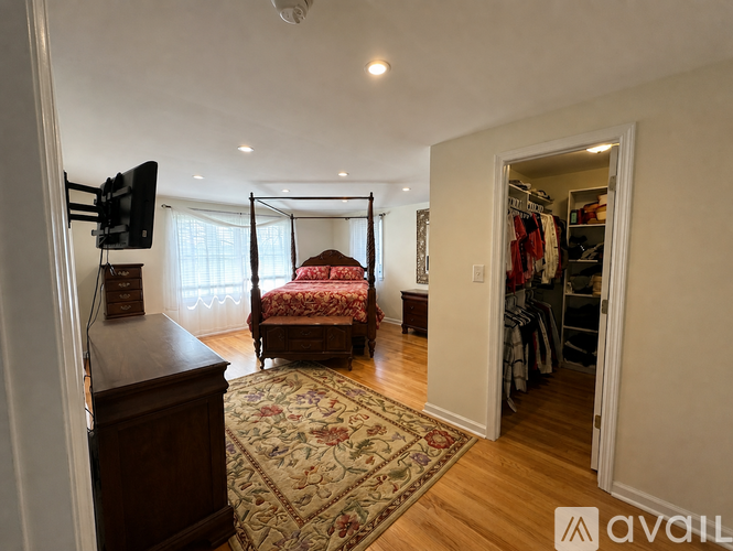 A bedroom with a four poster bed and a television on a stand.