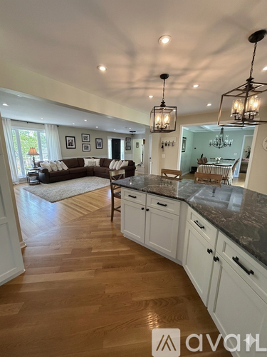 A modern kitchen with wooden floors and white cabinets.