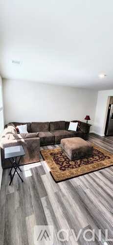 A living room with a grey sofa and a brown rug.
