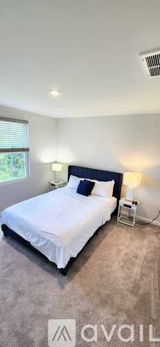 A bedroom with a large bed and a nightstand with a lamp.