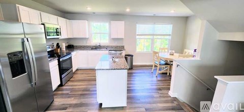 A kitchen with white cabinets and a stainless steel refrigerator.