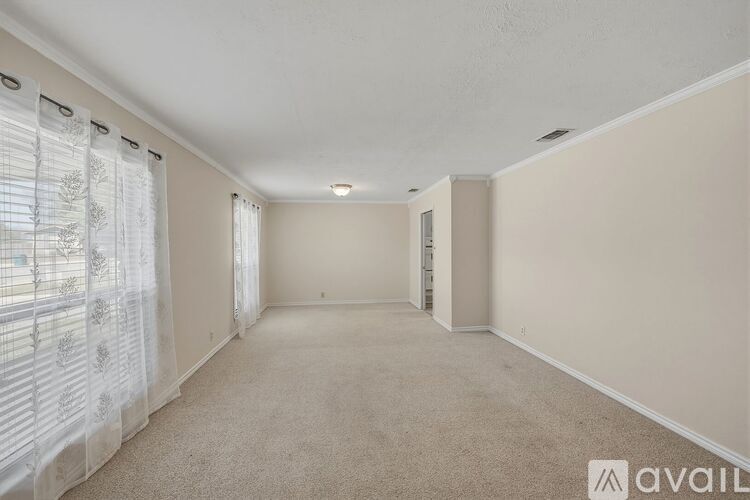 A spacious room with carpeted floor and white walls.