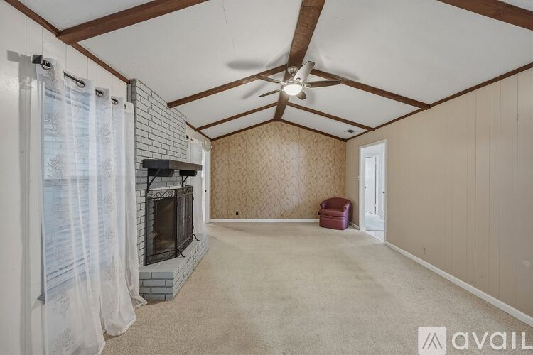 A living room with a fireplace and a fan on the ceiling.