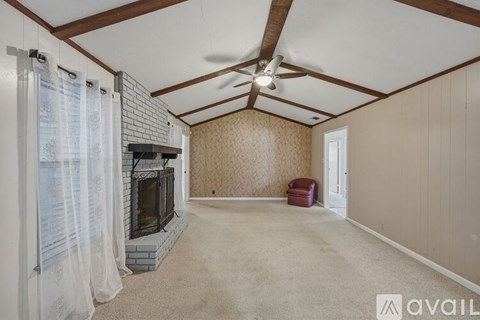 A living room with a fireplace and a fan on the ceiling.