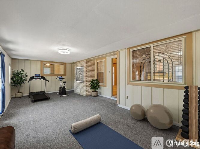 A spacious room with a treadmill, exercise balls, and a yoga mat.