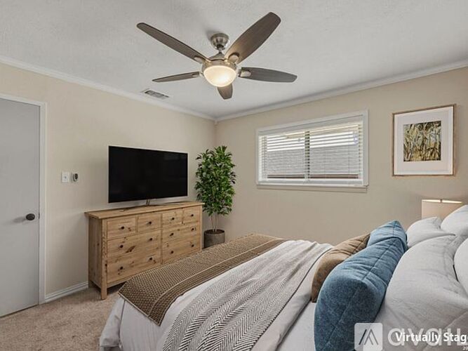 A bedroom with a bed, a dresser, a ceiling fan, and a window.