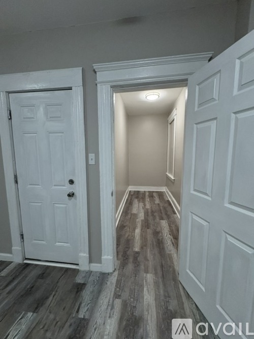 A hallway with a white door and a white wall.