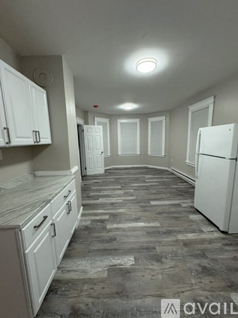 A kitchen with white cabinets and a refrigerator.