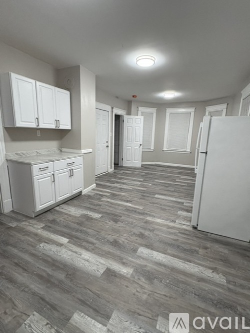 A kitchen with white appliances and cabinets with a grey floor.