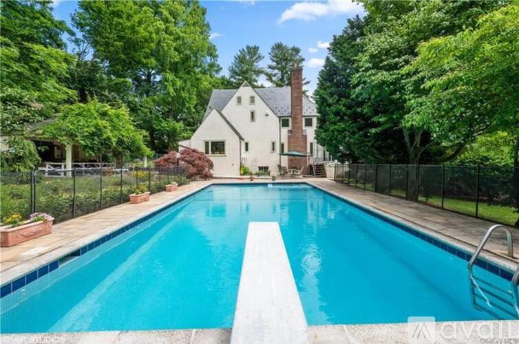 A swimming pool in front of a house surrounded by a fence.