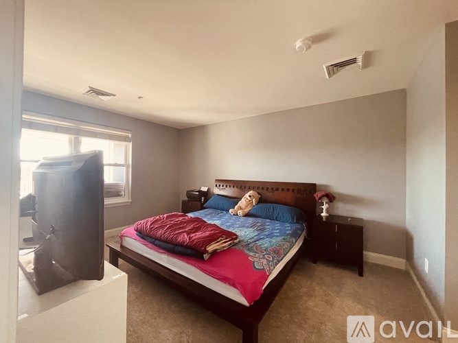 A bedroom with a bed, nightstand, and window.